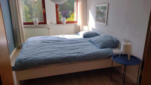 a bed in a bedroom with two windows and a table at Hochwald-Balkon in Bad Sachsa