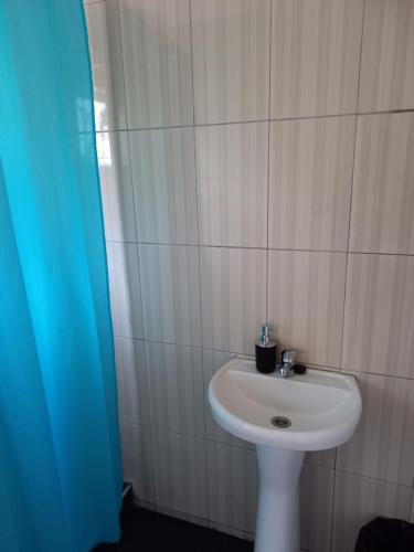 uma casa de banho com um lavatório branco e uma cortina de chuveiro azul em 2 Bedroom Residential Home, along the coast. em Durban