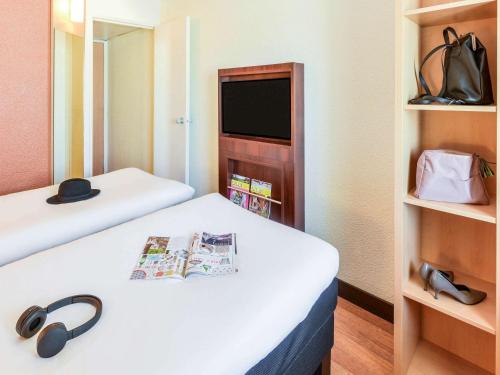 um pequeno quarto com duas camas e uma televisão em ibis Clermont Ferrand Montferrand em Clermont-Ferrand