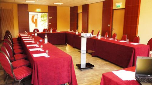 a conference room with red tables and chairs and a laptop at The Originals City, Hôtel Ascotel, Lille Est Grand Stade in Villeneuve d'Ascq