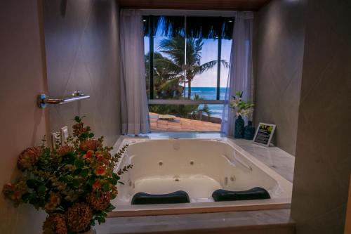 y baño con bañera y ventana. en Pousada Cocoa, en Pirangi do Norte