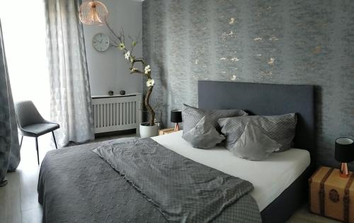 een slaapkamer met een bed met een grijze deken en kussens bij Apartament -Sweet Home in Lubin