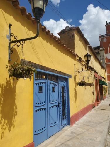 a yellow building with a blue door on a street at Casa Carmen in San Cristóbal de Las Casas