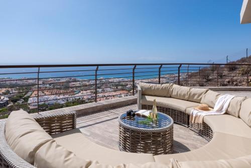 einen Balkon mit Sofas, einem Tisch und Meerblick in der Unterkunft Luxury Villa María private heated pool in Adeje