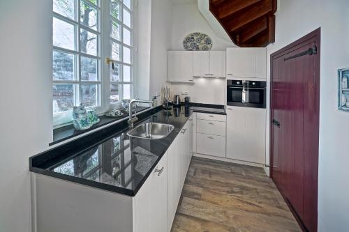 a kitchen with white cabinets and a sink at Hotel Abdijhof Thorn in Thorn