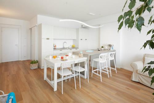 a white kitchen with a white table and chairs at Maison del Bassotto in Numana