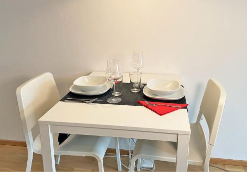 ein weißer Tisch mit weißen Tellern und Gläsern darauf in der Unterkunft Holiday Suites Sankt Martin in Klagenfurt am Wörthersee