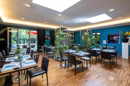 ein Restaurant mit Tischen, Stühlen und Pflanzen in der Unterkunft The New Yorker Hotel Köln-Messe in Köln