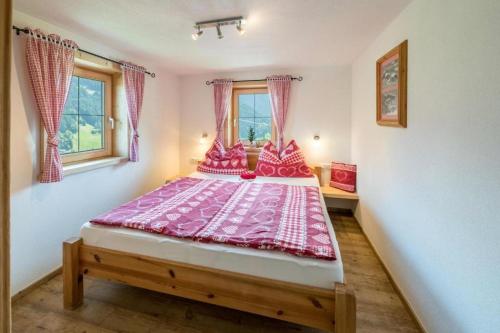 ein Schlafzimmer mit einem großen Bett mit rosa Bettwäsche in der Unterkunft Biohof Vorderreith in Jochberg