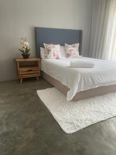 a bedroom with a bed with a nightstand and a white rug at Maso palace in Polokwane