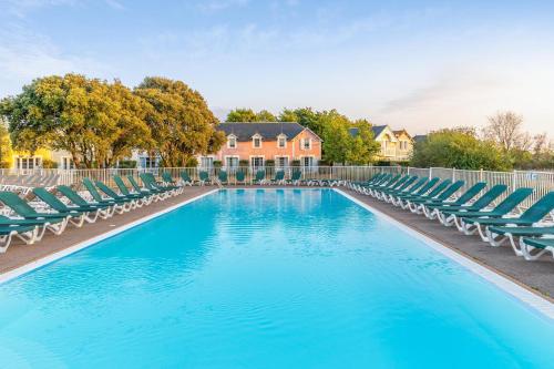 a swimming pool with lounge chairs and a house at Résidence Pierre & Vacances Le Domaine de Bourgenay in Talmont