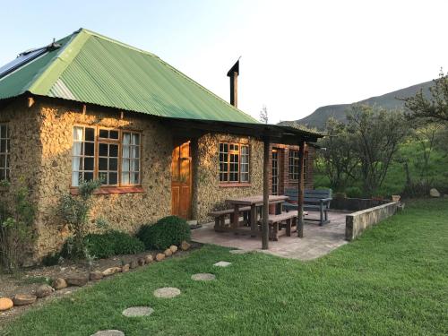a stone house with a picnic table and a bench at Sani Lodge Self-Catering Cottages Sani Pass South Africa in Sani Pass