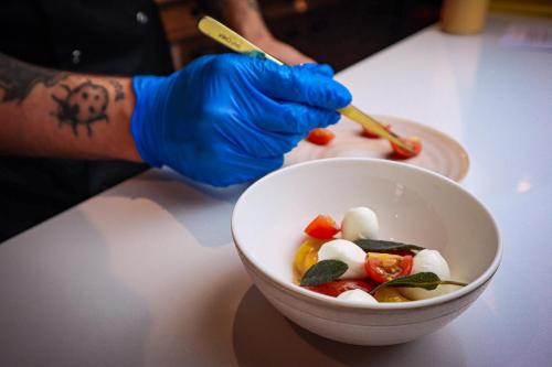 a person in blue gloves holding a bowl of food at Lion & Swan Hotel in Congleton