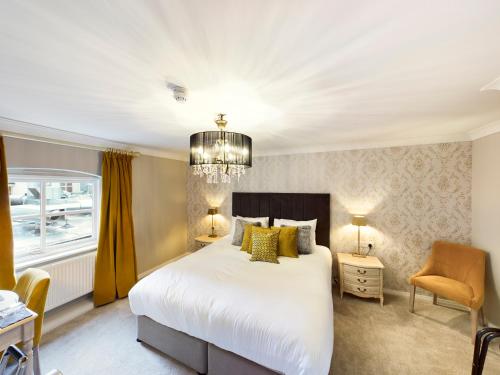 a bedroom with a large white bed and a chandelier at Lion & Swan Hotel in Congleton