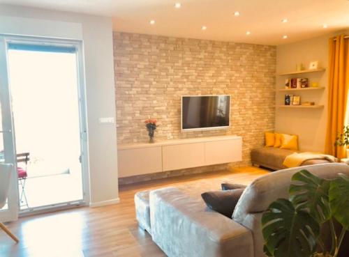 a living room with a couch and a tv on a brick wall at Beautiful view apartment with garage space in Mali Lošinj
