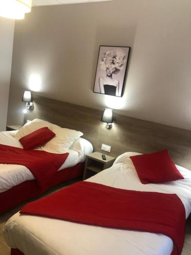 Cette chambre d'hôtel comprend 2 lits avec des oreillers rouges. dans l'établissement Hôtel Le Roi Gourmand, à Pamiers