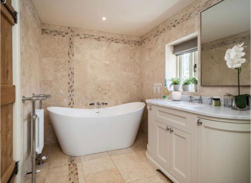 a bathroom with a white tub and a sink at Deer View cottage in Salhouse