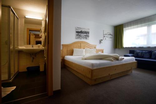 ein Schlafzimmer mit einem Bett und ein Badezimmer mit einem Waschbecken in der Unterkunft Alpenstern Pension Suites in Lermoos