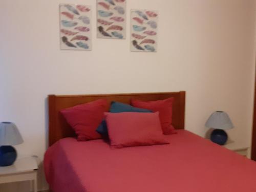sypialnia z łóżkiem z czerwoną pościelą i poduszkami w obiekcie Apartamento na Praia w mieście Carvoeiro
