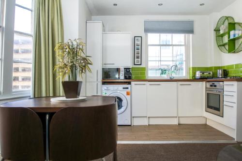 una cocina con armarios blancos y una mesa con una planta. en Cannon Place - Central - by Brighton Holiday Lets, en Brighton & Hove