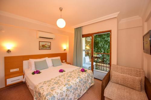a bedroom with a bed and a chair and a window at Perdikia Hill Hotel And Villas in Oludeniz