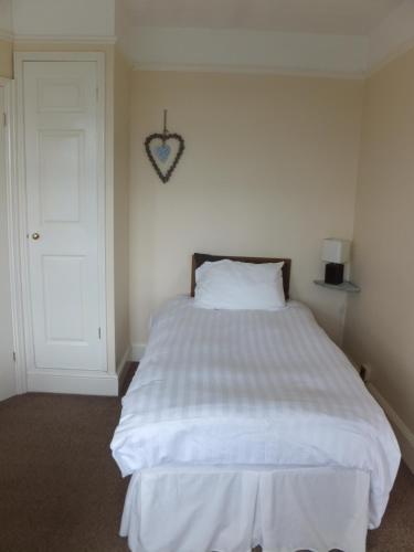 a bedroom with a white bed with a heart on the wall at Sea Jade Guest House in Bude