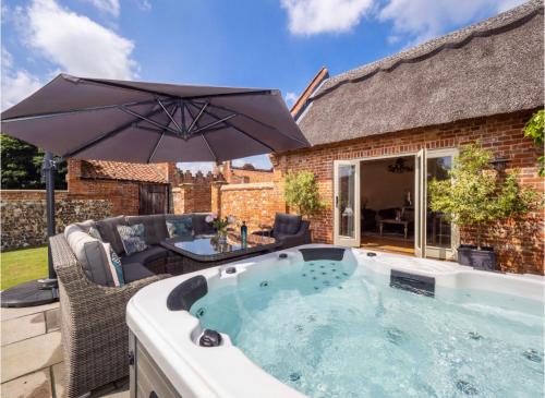 a hot tub with an umbrella on a patio at Deer View cottage in Salhouse