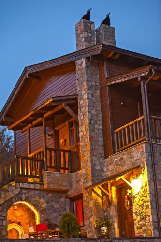 a large stone house with a wrap around porch at Suites Efharis Filoxenon in Feneos
