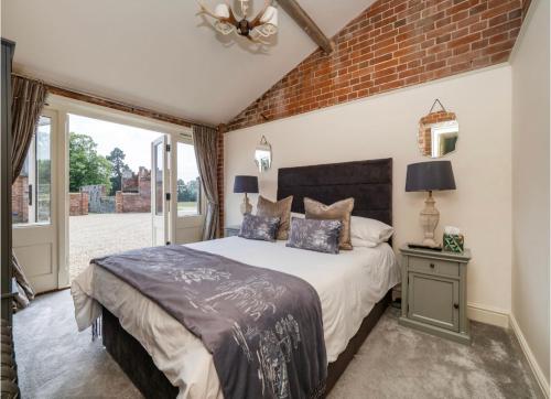 een slaapkamer met een bed en een bakstenen muur bij Enchanted Cottage in Salhouse