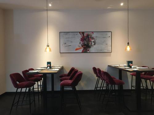 a dining room with two tables and red chairs at Holiday Inn Berlin City Center East Prenzlauer Berg, an IHG Hotel in Berlin