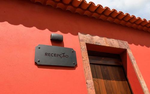a sign on the side of a red building with a window at QUINTA DO FALCÃO in Almagreira