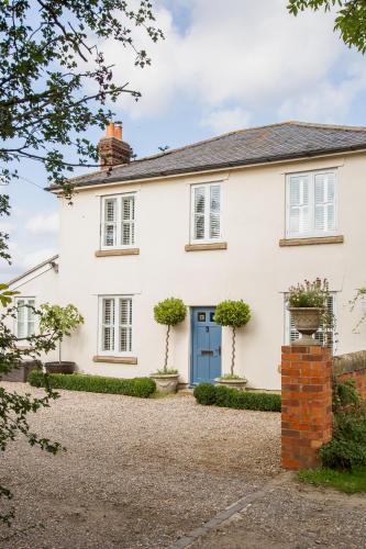 a white house with a blue door at SmallBrook Cottage in Broadway