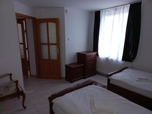 a bedroom with two beds and a window and a door at Krisztina Apartman 1- Szigethalom in Szigethalom