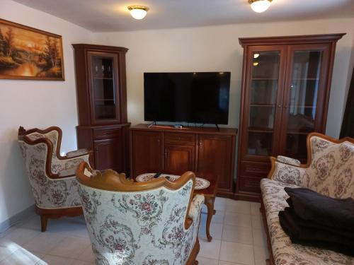 a living room with a flat screen tv and chairs at Krisztina Apartman 1- Szigethalom in Szigethalom
