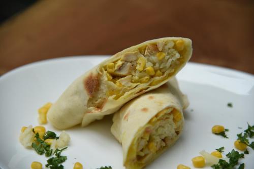 a white plate with a burrito with corn on it at Hotel Bela Kuka in Bitola