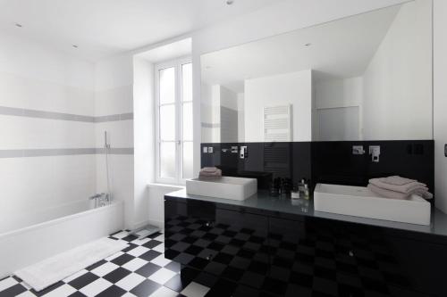 un bagno in bianco e nero con due lavandini e una vasca di Maison Le Clos Neraud avec piscine et SPA a Saint-Martin-de-Ré