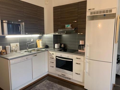 cocina con armarios blancos y nevera blanca en Modern Apartment with Sauna Nearby Airport, en Vantaa