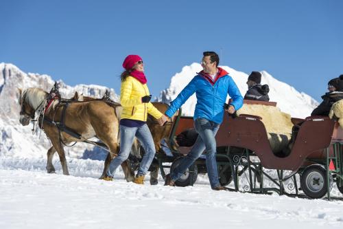 a man and a woman pulling a horse drawn carriage in the snow at Binterhof in Castelrotto