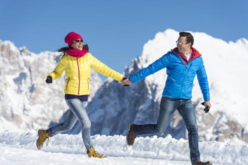a man and a woman running in the snow at Binterhof in Castelrotto