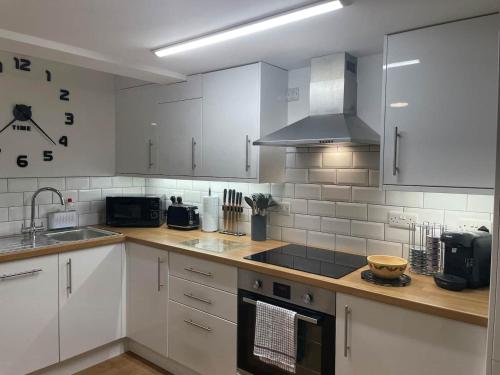 uma cozinha com armários brancos e um forno com placa de fogão em The Garden Apartment em Newton Abbot
