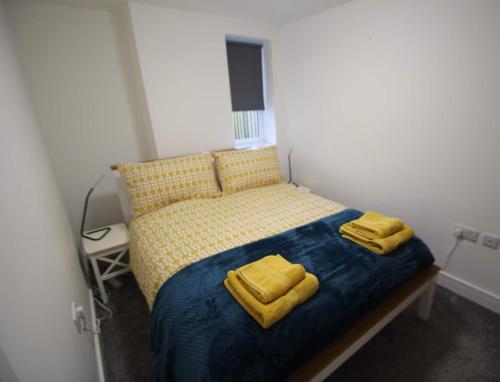 sypialnia z łóżkiem z dwoma żółtymi ręcznikami w obiekcie The Garden Apartment w mieście Newton Abbot