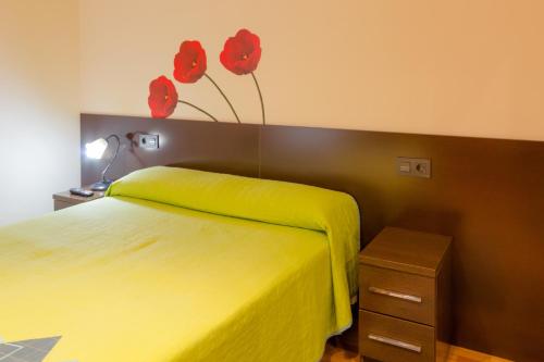 a bedroom with a yellow bed with red flowers on the wall at Pension Logroño in Logroño