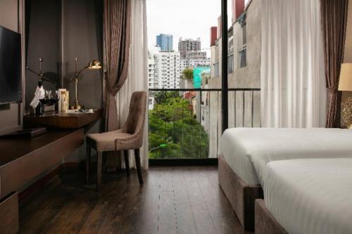 Pokój hotelowy z łóżkiem, biurkiem i oknem w obiekcie PING DIAMOND HOTEL w mieście Hanoi