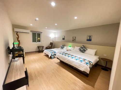 ein Hotelzimmer mit 2 Betten und einem Schreibtisch in der Unterkunft 墾丁聚點旅棧 2Ps Hotel in Kenting