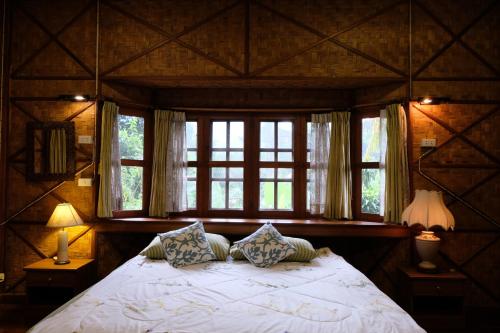 a bedroom with a large bed with two windows at Ashi Guesthouse Chiangdao in Chiang Dao