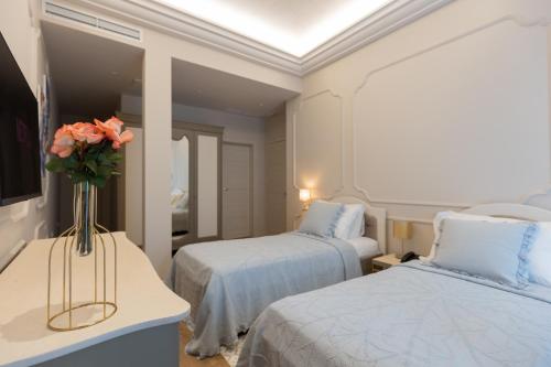 a hotel room with two beds and a vase of flowers at Hotel Boutique Vila 135 in Tirana