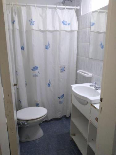 a bathroom with a toilet and a sink and a shower curtain at AMANECERES LAS GRUTAS II in Las Grutas
