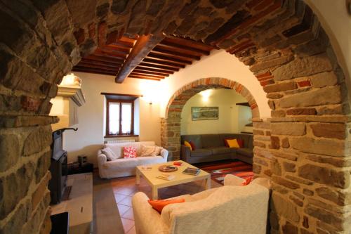 a living room with a stone wall and a living room with a table at Casale Lorenzo in Subbiano