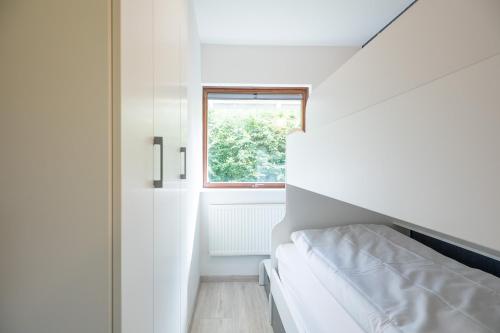 a small white room with a bed and a window at Friesenkrabbe in Almdorf