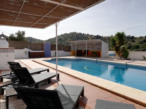 - une piscine avec 2 chaises et une maison dans l'établissement B&B Casa El Corasueño, à Almogía